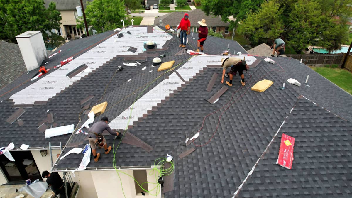 Handy Hands crew installing GAF shingles over FeltBuster synthetic underlayment on a Bellaire, TX roof