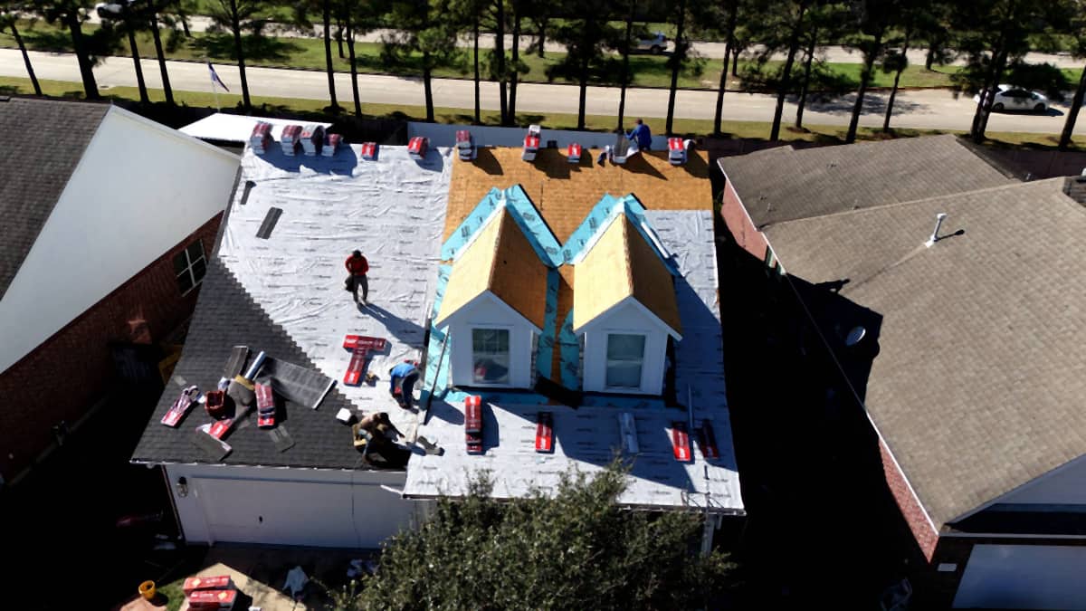 Aerial view of a Cypress, TX roof mid-installation, with synthetic underlayment across the main slopes and self-adhered membrane along the dormer valleys and rake edges