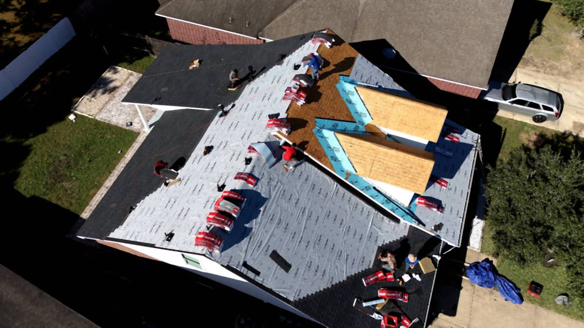 Aerial view of a Cypress, TX roof replacement with the first shingle courses going down over synthetic underlayment