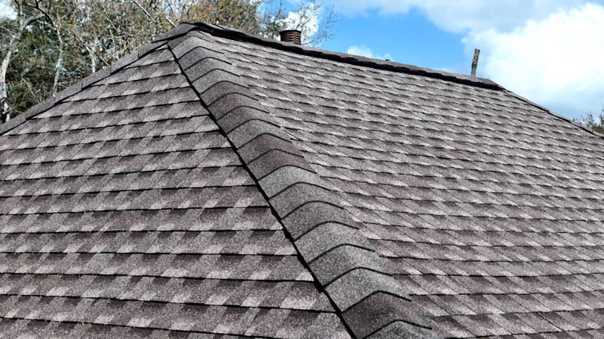 Finished shingle slope and ridge caps running against a blue sky on a Cypress, TX roof replacement