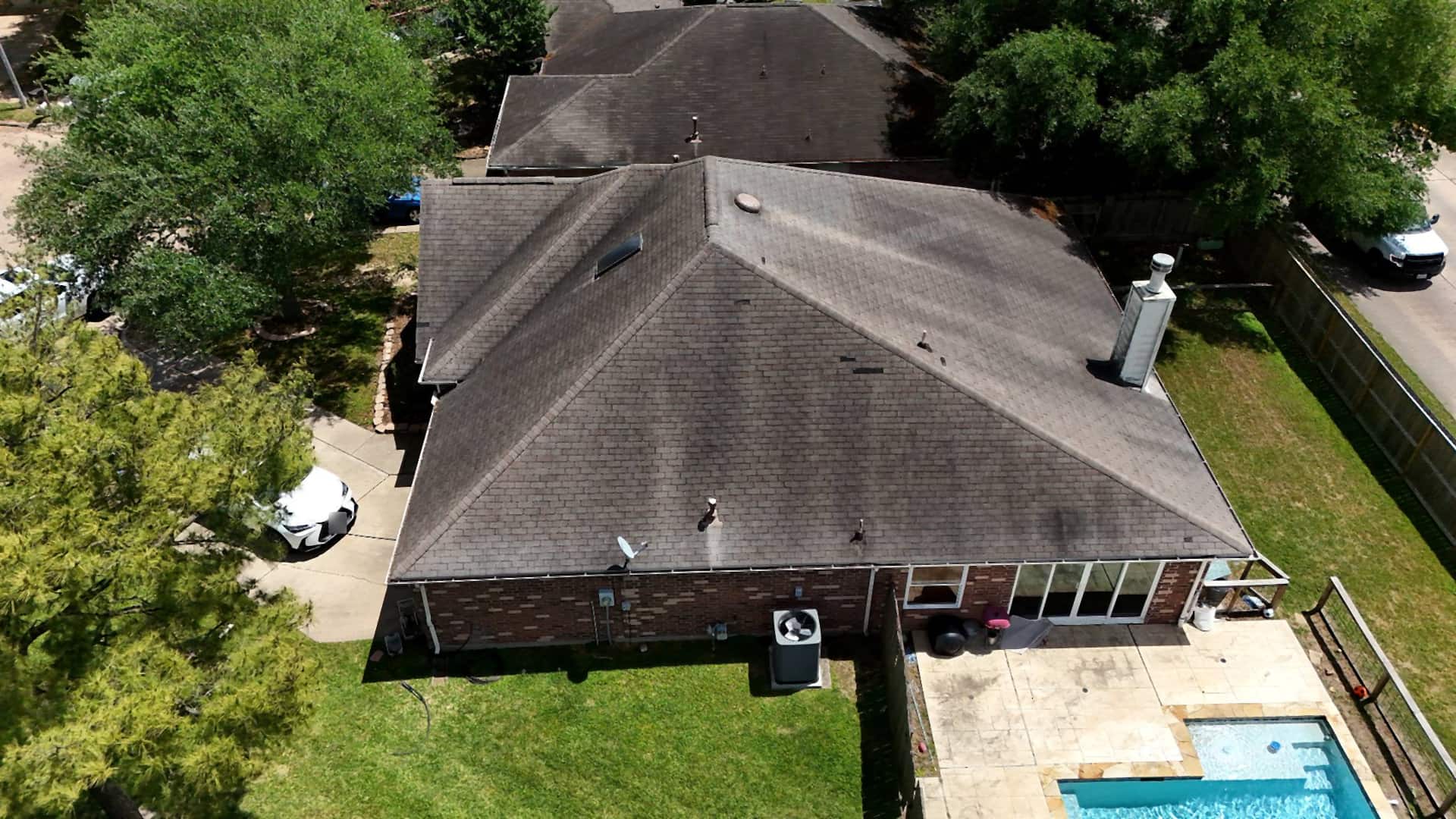 Weathered, streaked brown shingle roof on a Katy, TX home before replacement