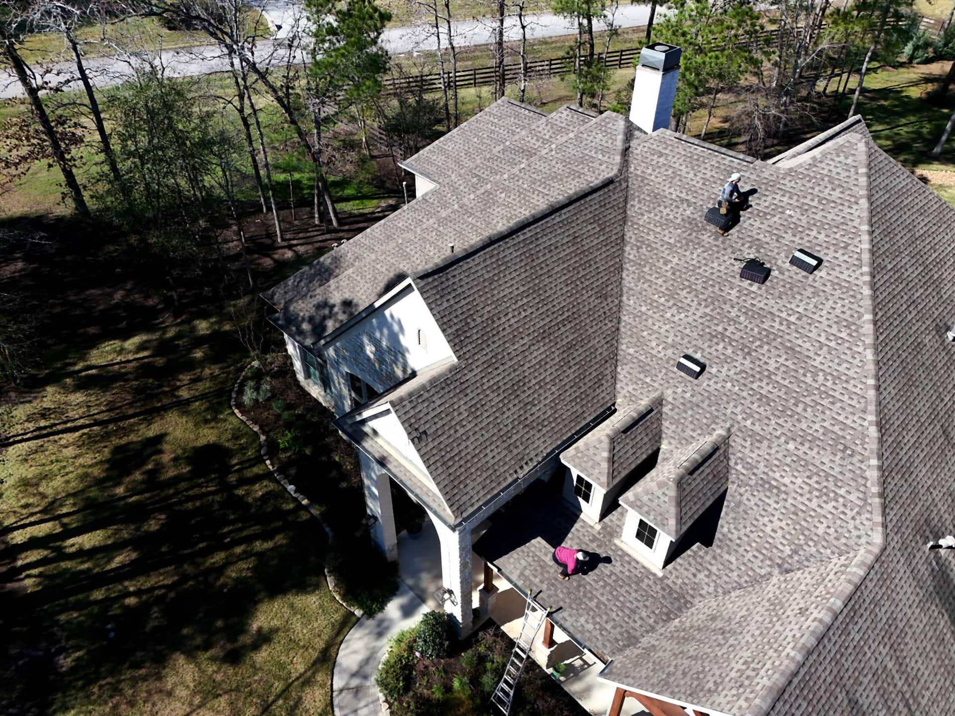 Aerial view of a large Magnolia, TX home on a wooded lot with a completed shingle roof replacement