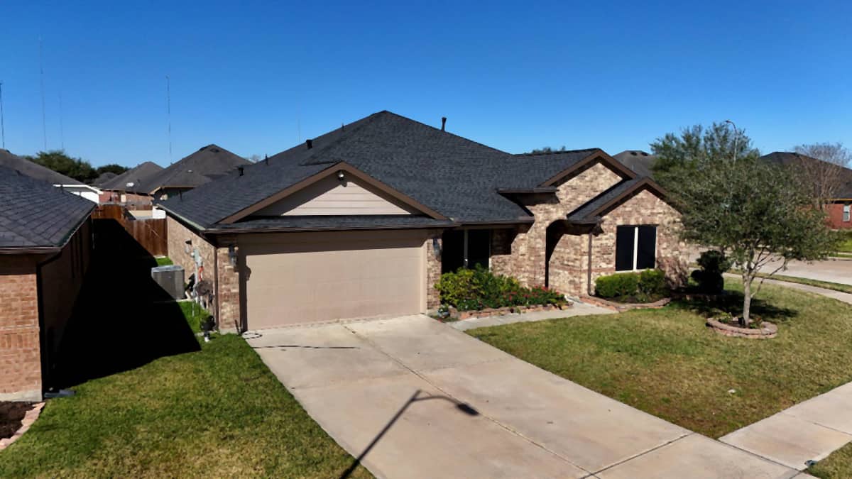 Brick home in Missouri City, TX with a completed dark charcoal shingle roof replacement