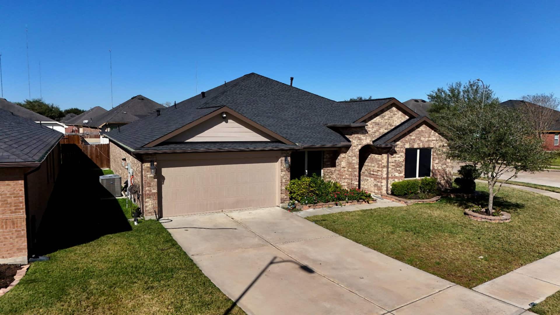 Brick home in Missouri City, TX with a completed dark charcoal shingle roof replacement