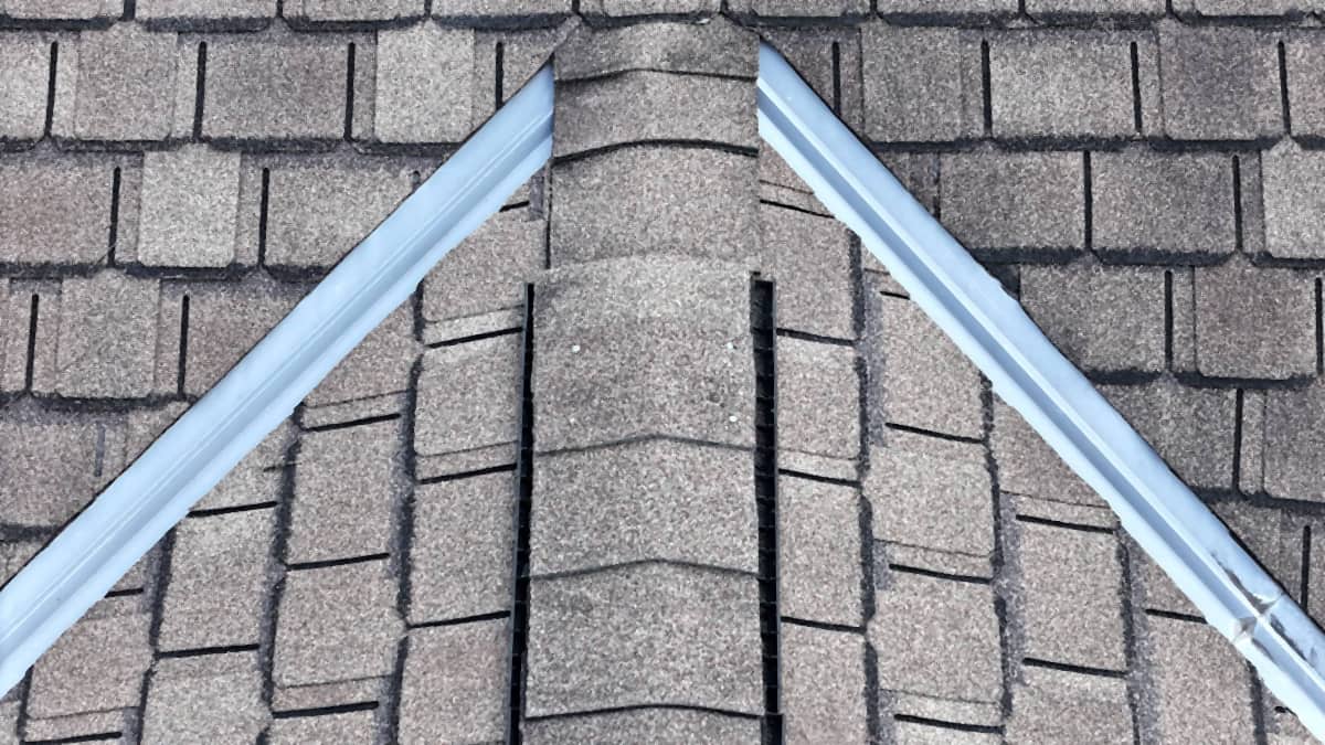 New metal running both rake edges up to the peak of a Montrose, Houston roof, with shingle ridge caps down the hip between them