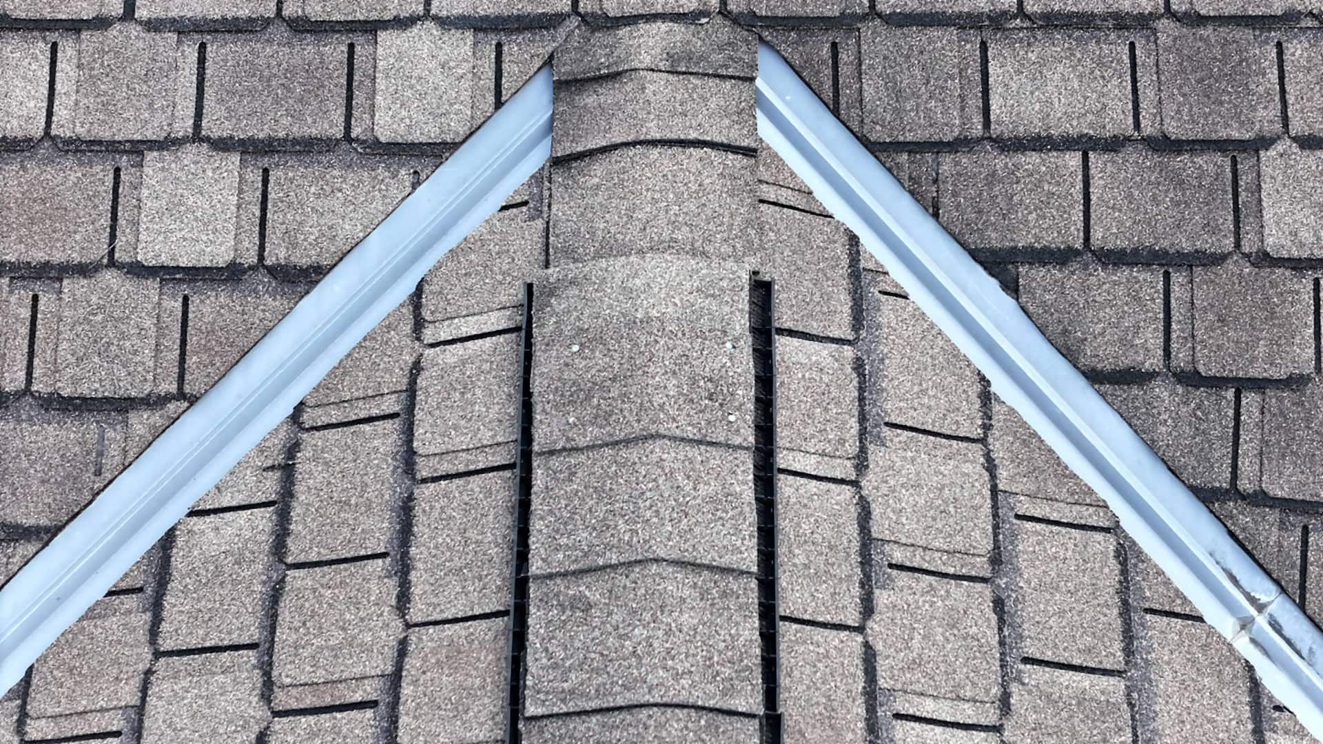 New metal running both rake edges up to the peak of a Montrose, Houston roof, with shingle ridge caps down the hip between them