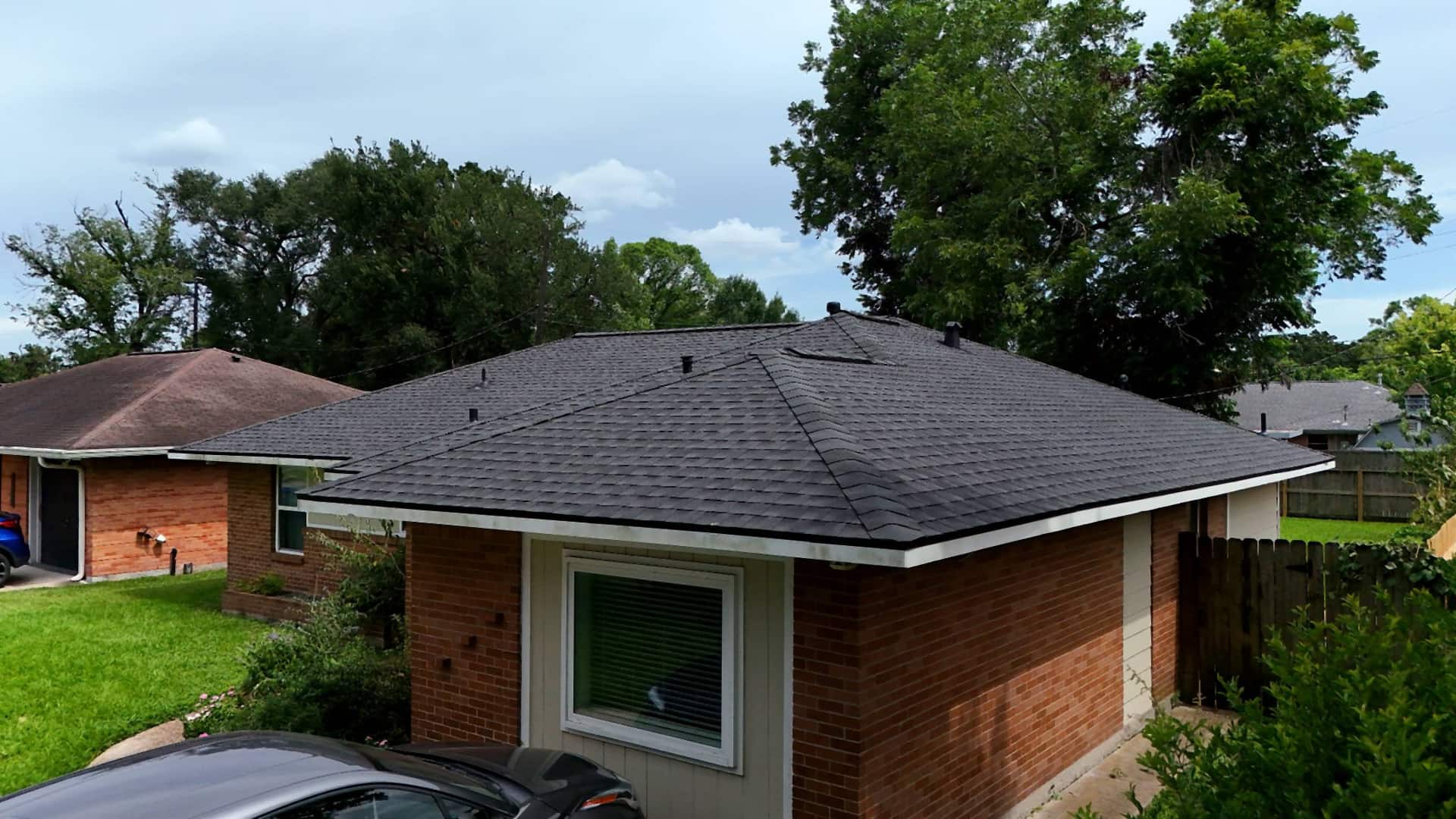 Street-level corner view of a brick Oak Forest, Houston home with a completed near-black shingle roof