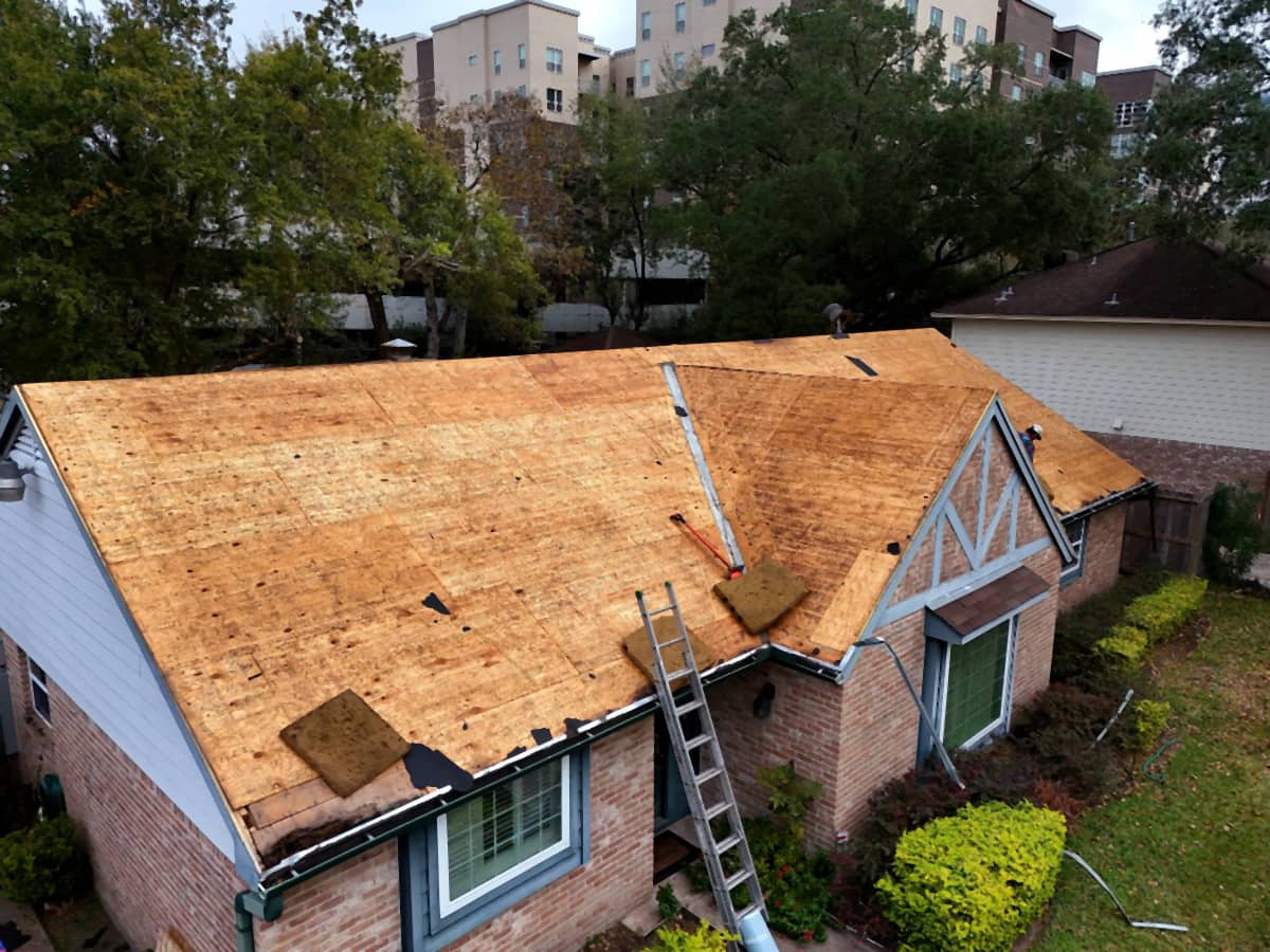 Aerial view of a Spring Branch, Houston home stripped to bare plywood roof decking during a replacement