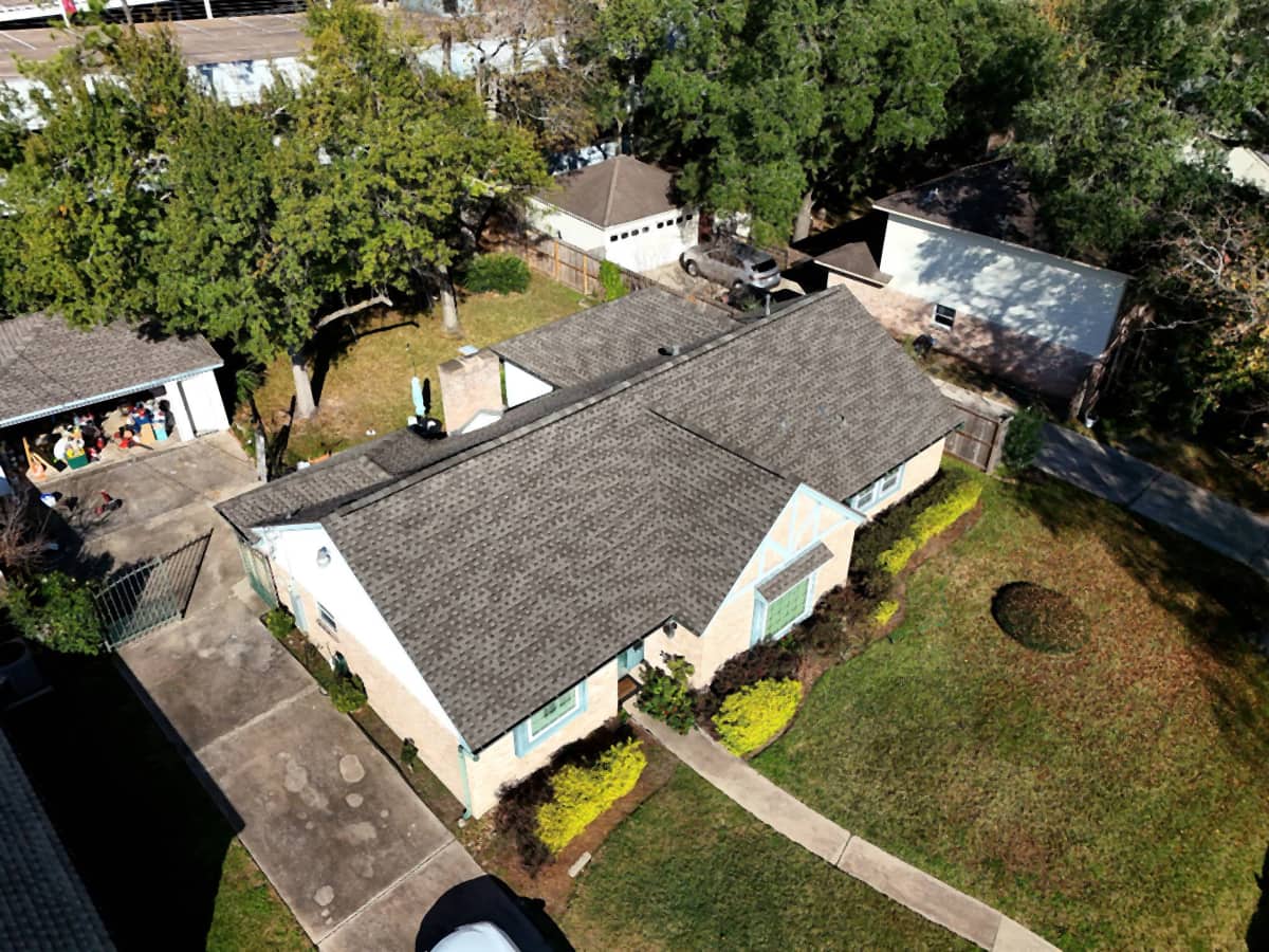Completed brown shingle roof replacement on a Spring Branch, Houston home with teal trim — aerial oblique view