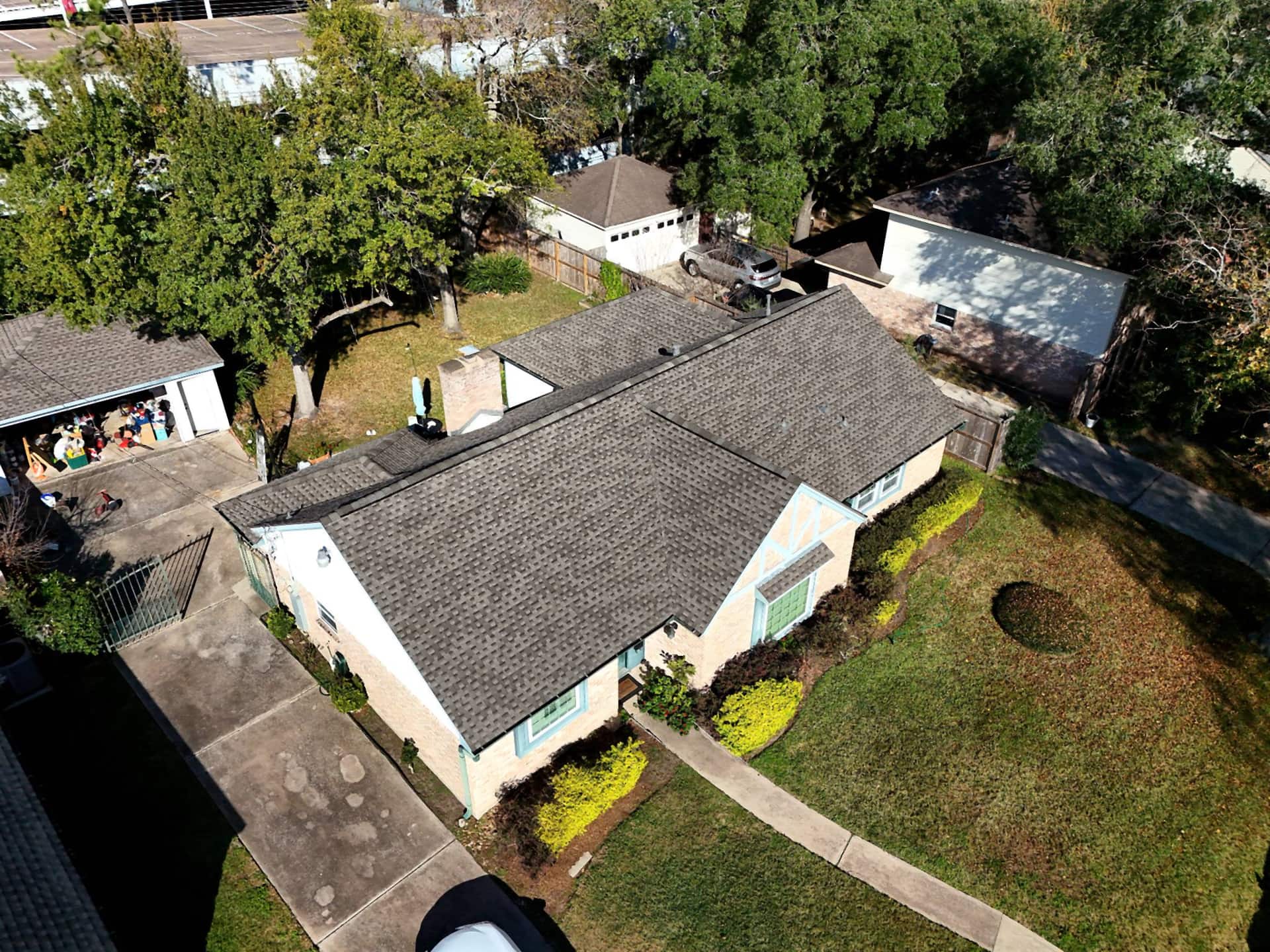 Completed brown shingle roof replacement on a Spring Branch, Houston home with teal trim — aerial oblique view