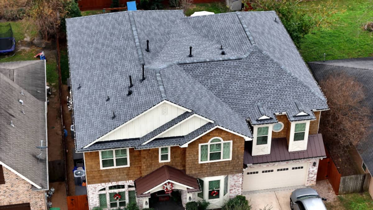 Aerial view of a completed gray shingle roof replacement on a two-story Timbergrove home in Houston