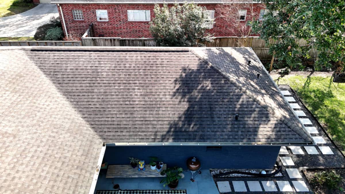 Overhead view of a completed brown shingle roof and new drip edge above a back patio on a Westbury, Houston home